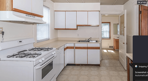 A kitchen with white cabinets and a white stove top oven.