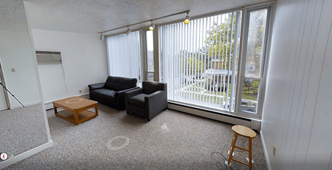 A living room with a black couch and a wooden stool.