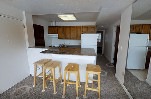 A kitchen with a white fridge and wooden stools.