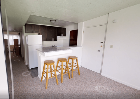 A kitchen with a white fridge and wooden stools.