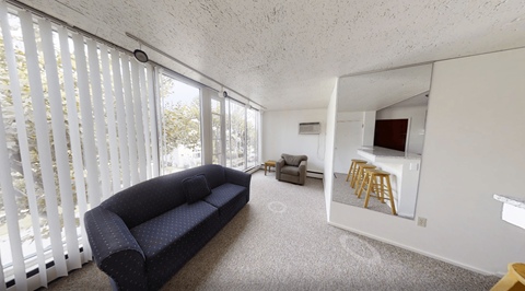 A living room with a couch, a chair, and a small kitchenette.