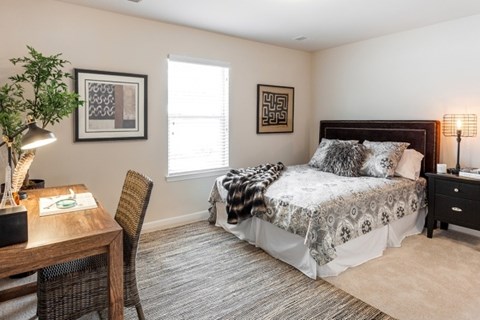 A bedroom with a bed, chair, and lamp.