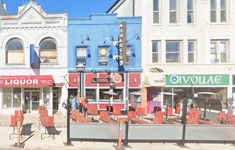 A street view with a liquor store, a bar, and a store with a green awning.
