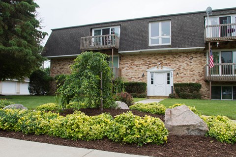 the front yard of a brick house with a lawn and landscaping