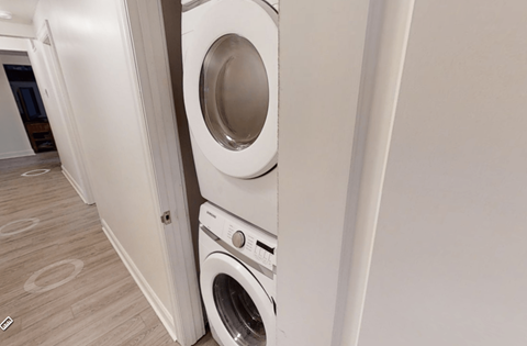 A white washing machine is stacked on top of another in a laundry room.