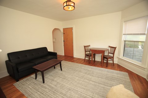 A black couch sits in a living room with a wooden coffee table in front of it.