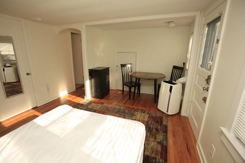 A bedroom with a bed, table and chairs.