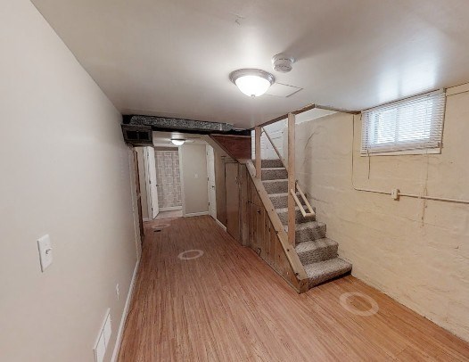 A room with wooden flooring and a staircase leading to another room.
