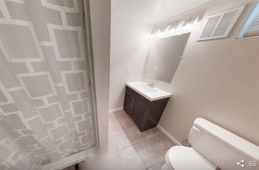 A small bathroom with a toilet, sink, and shower curtain.