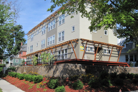 A building with a balcony and a red brick wall in front.