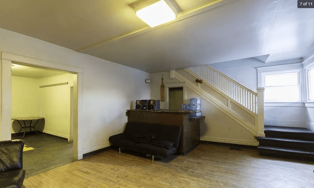 A living room with a black couch and a wooden floor.