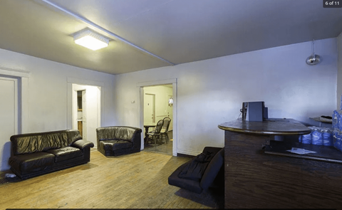 A living room with a couch, chair, and a table with a bottle on it.