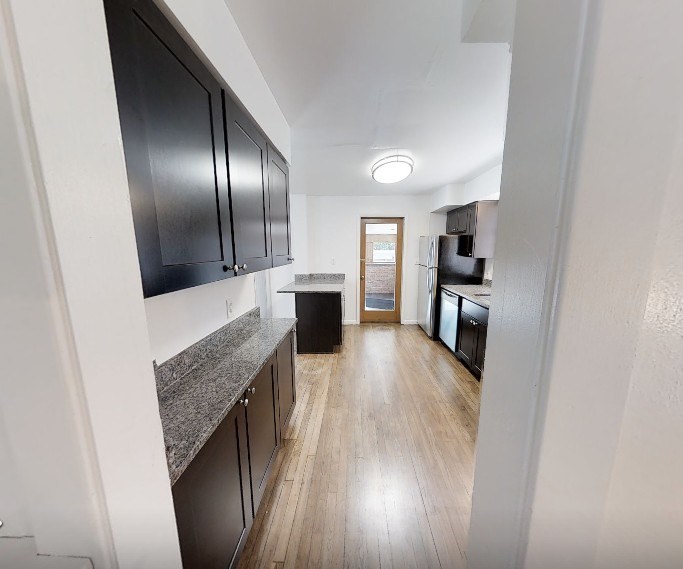 A kitchen with black cabinets and a wooden floor.