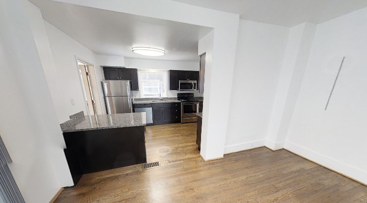 A kitchen with a refrigerator, stove, and sink is visible from the living room.