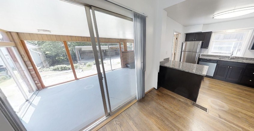 A modern kitchen with a large island and a view of the backyard through the sliding glass doors.