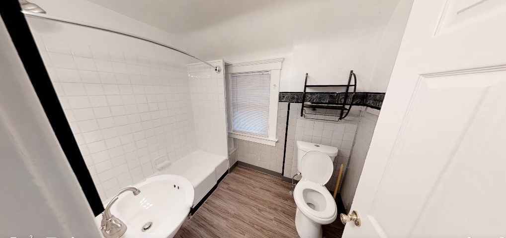 A white toilet is in a bathroom with a white bathtub and a white sink.