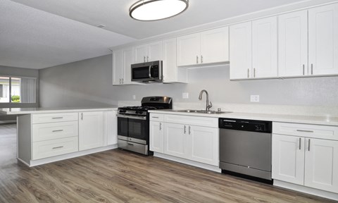 A modern kitchen with white cabinets and stainless steel appliances.