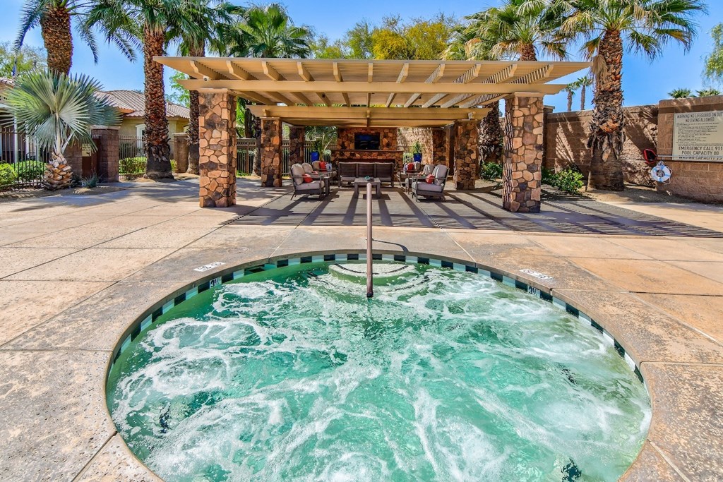 A hot tub in the middle of a patio with a pergola above it.