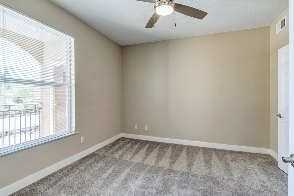 A room with a ceiling fan and carpeted floor.