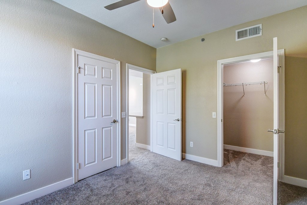 A room with a carpeted floor and three doors.