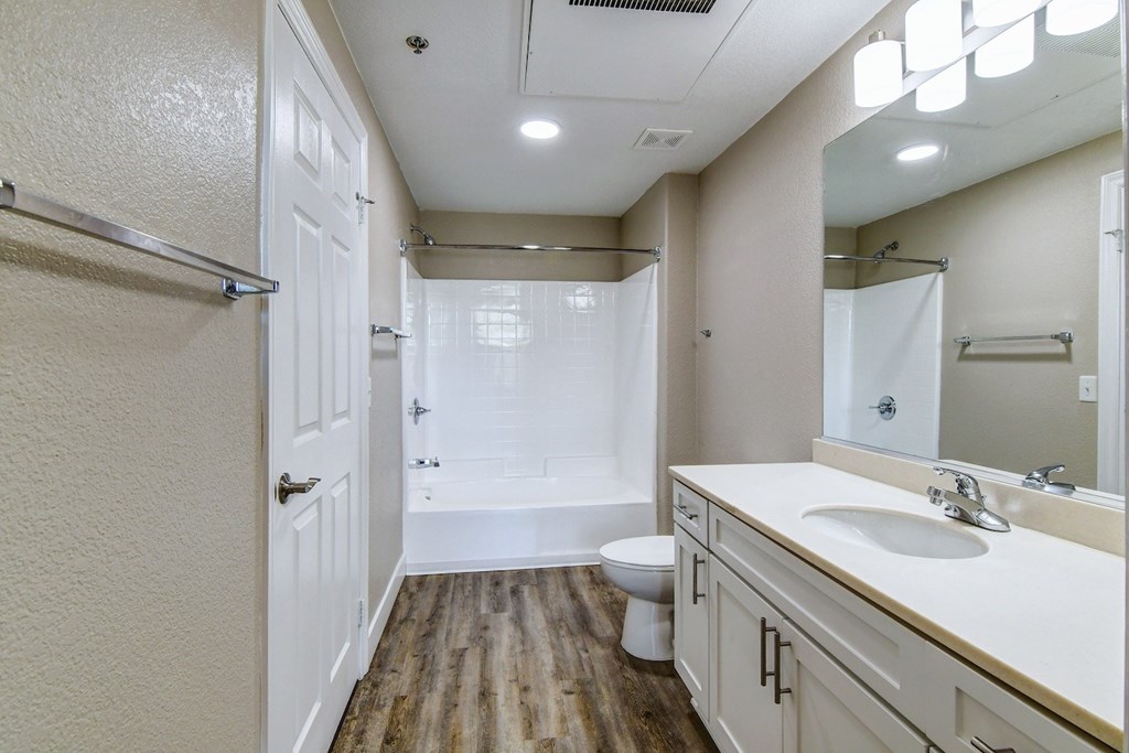 A bathroom with a toilet, sink, and mirror.