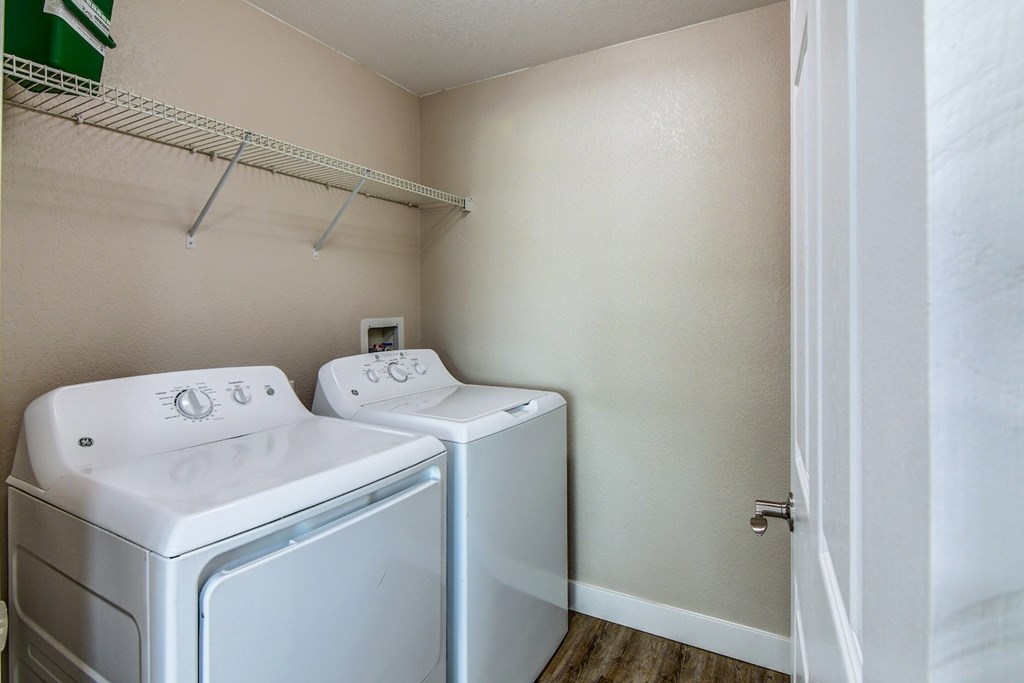 Two white front loading washing machines in a small laundry room.