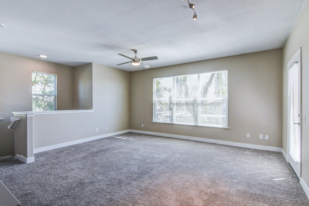 A spacious room with a ceiling fan and large windows.