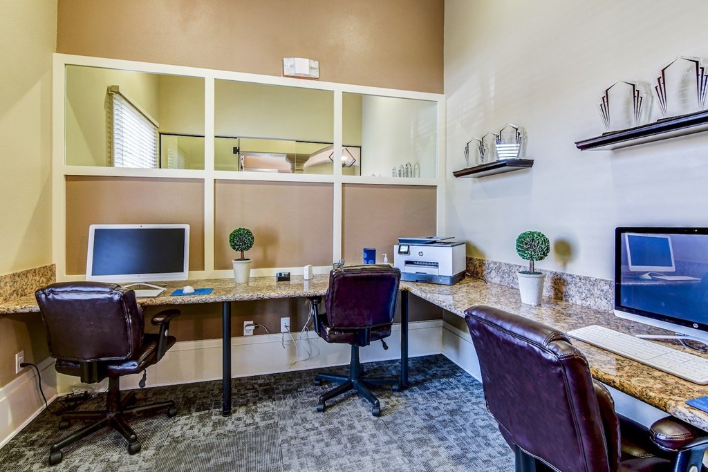 A home office with a desk, chairs, and computer monitors.