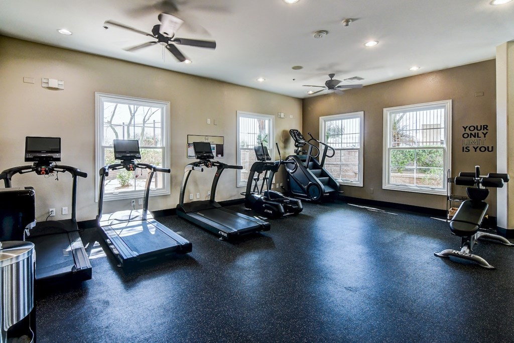 A spacious gym with a variety of equipment including treadmills, elliptical machines, and a weight bench.