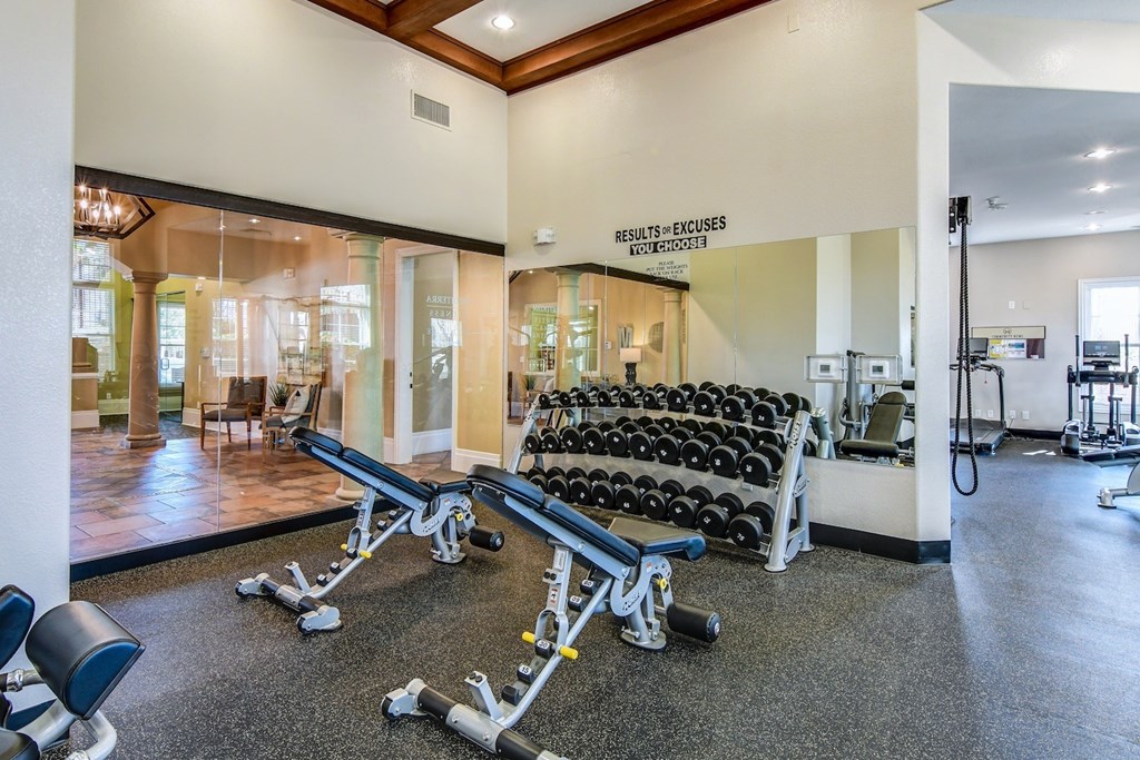 A gym with a row of dumbbells and a sign that says "Results = Excuses".