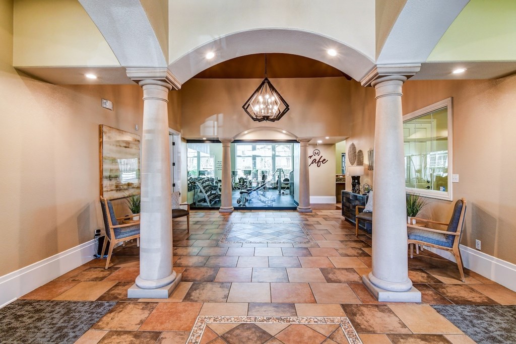 A hallway with a tiled floor and columns on either side.