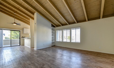 an empty living room with wood floors and a kitchen