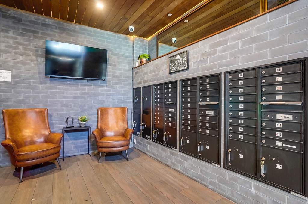 a lounge area with two leather chairs and a large gray brick wall with a television on top