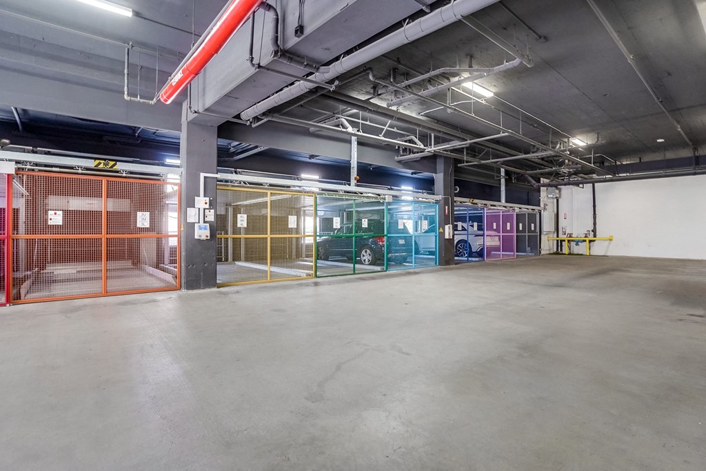 a parking garage with a green car in the distance and a red and yellow pole in the