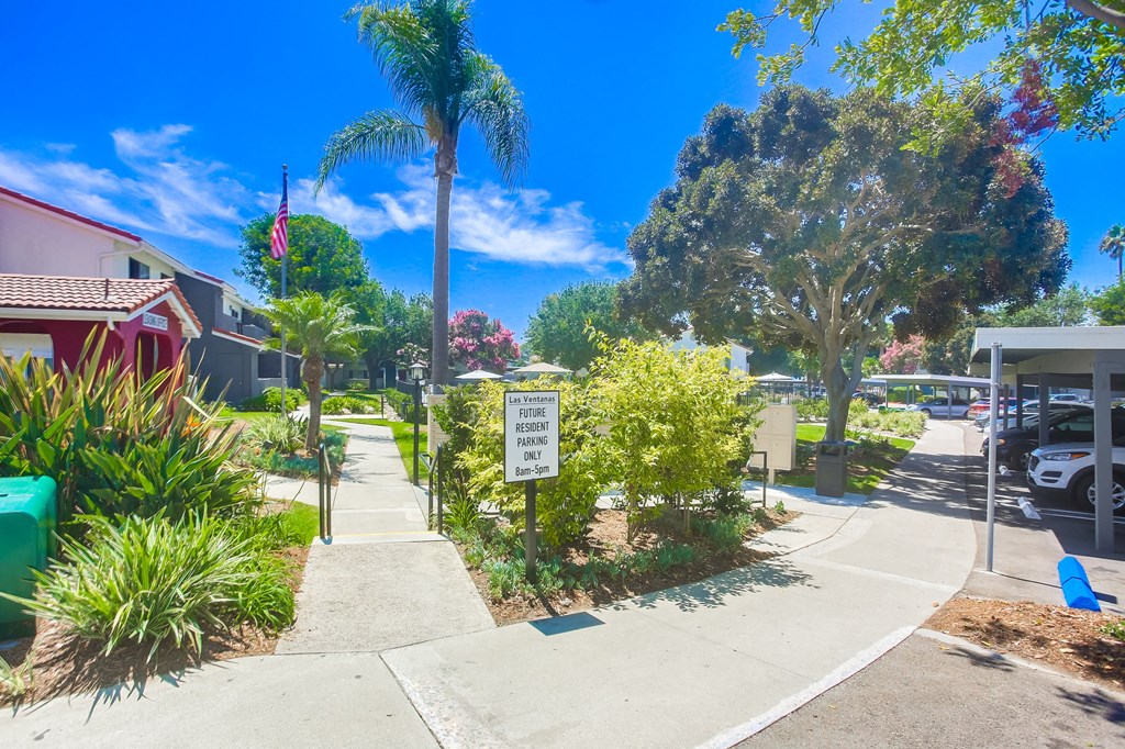 a sidewalk in front of a house with a sign on the sidewalk