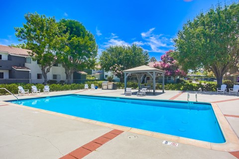 a swimming pool with a gazebo and chairs around it