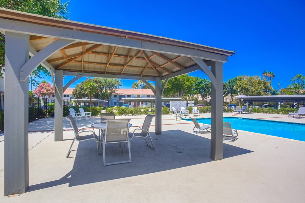 a patio with tables and chairs next to a swimming pool