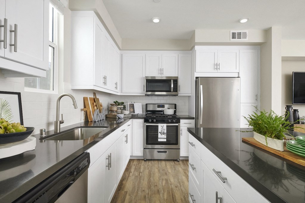 Apartments In Riverside, CA For Rent - Lincoln Village - Kitchen With Microwave, Stainless Steel Appliances, Dishwasher, Refrigerator, Gas Range Stove, Wood Style Flooring, And White Cabinets