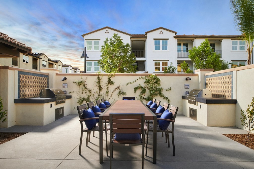 Riverside, CA Apartments for Rent - Lincoln Village - Gated BBQ Grilling Area With 10 Person Table, 2 Grills, Green Plants, And Stylish Decor