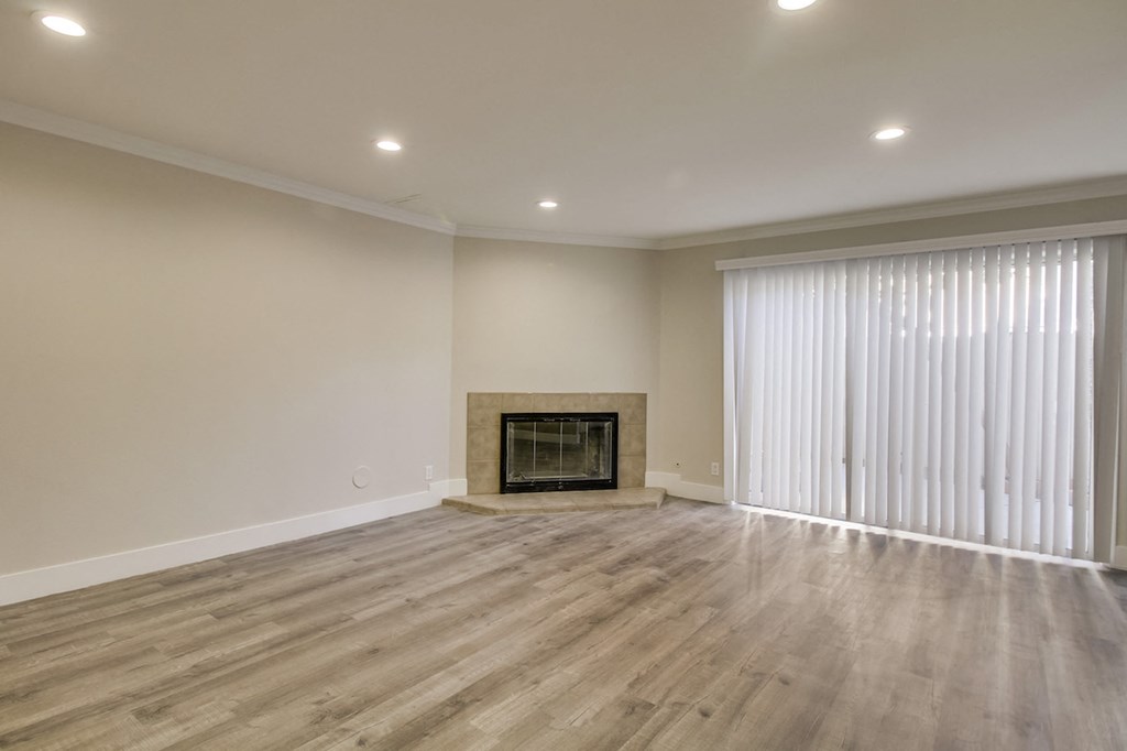 A spacious room with a fireplace and wood flooring.