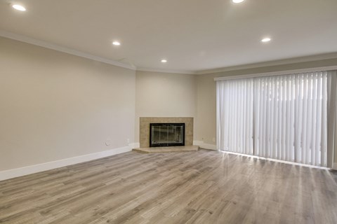 A spacious room with a fireplace and wood flooring.