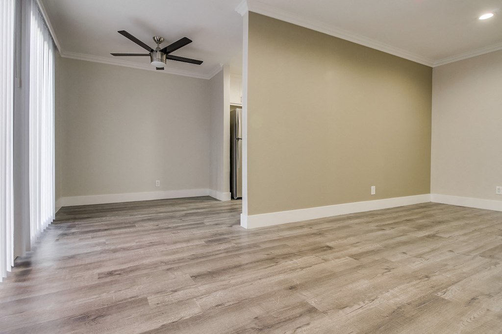 A room with new flooring and a ceiling fan and lighting fixture.