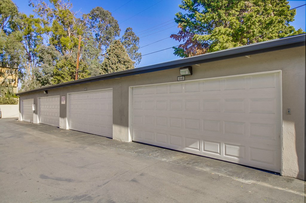 A row of white garage doors in front of a building.