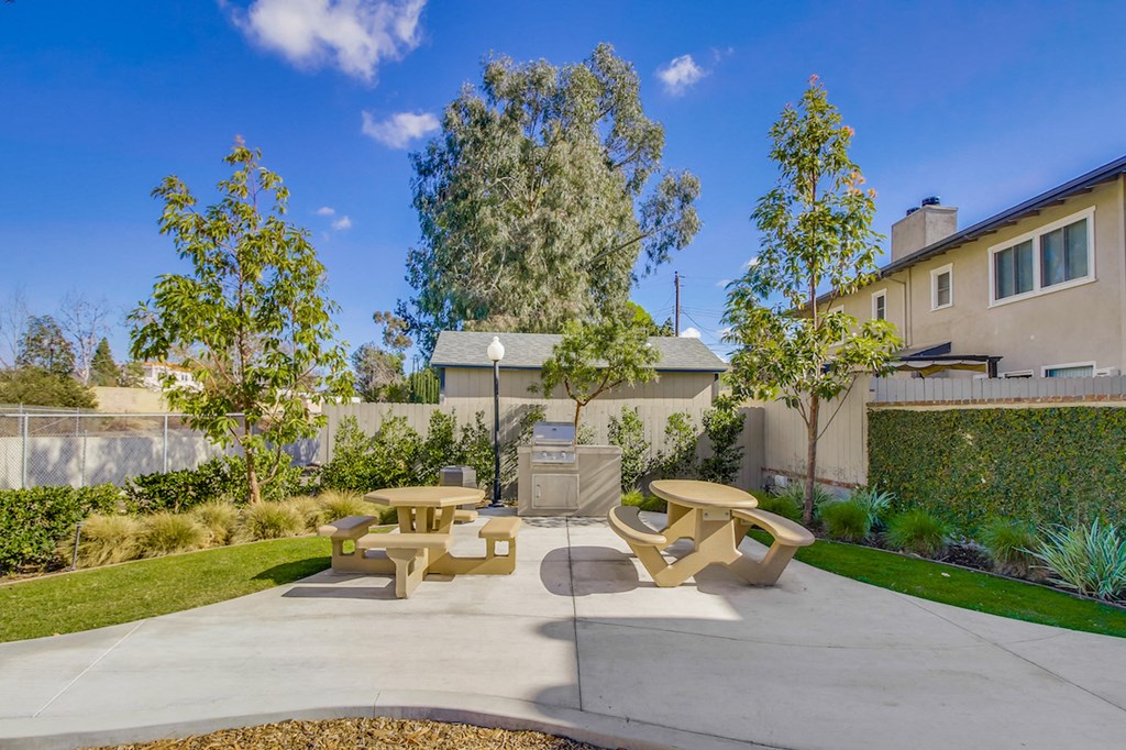 A sunny day at a park with picnic tables and benches.