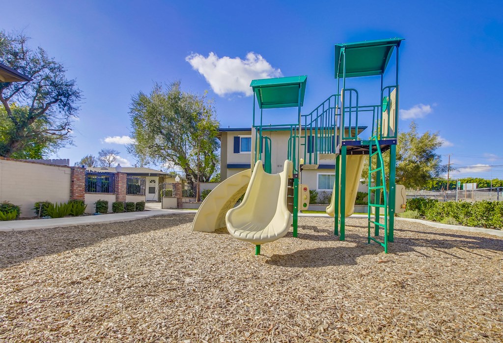 A playground with a slide and a green structure.