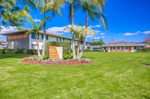 a building with palm trees and a sign in the grass
