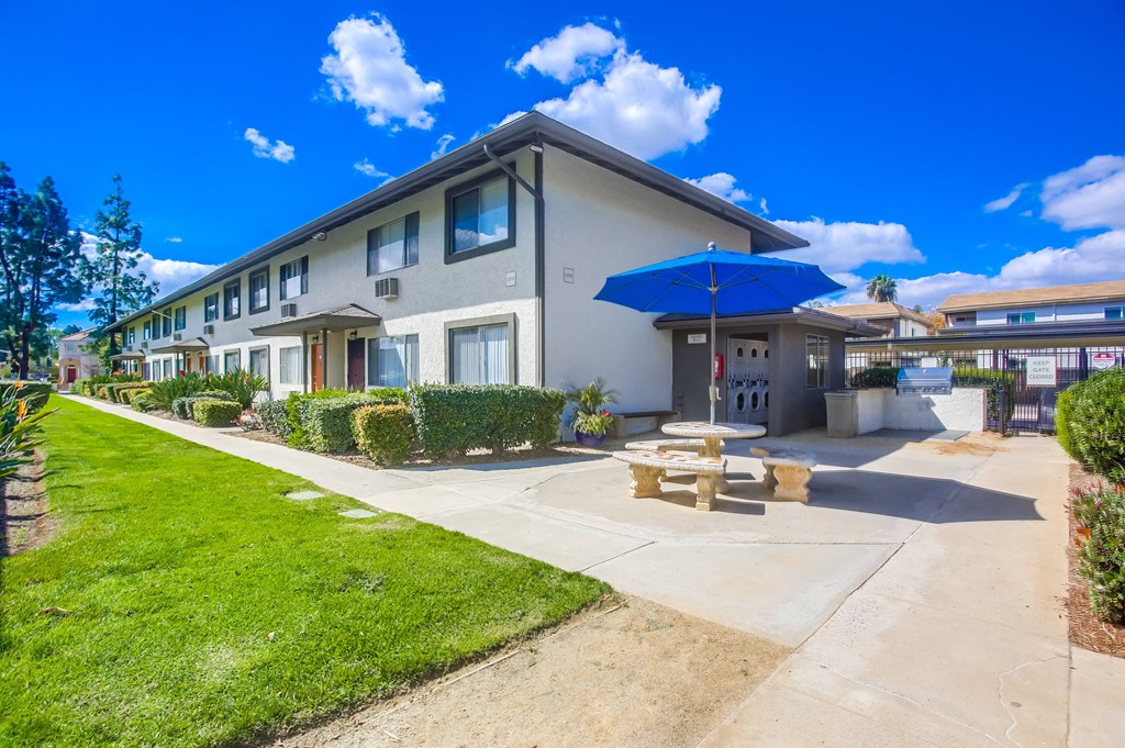 a patio with a table and umbrella outside of a building