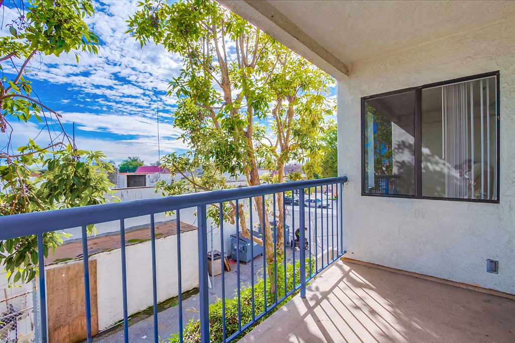 a balcony with a blue railing and a view of a tree