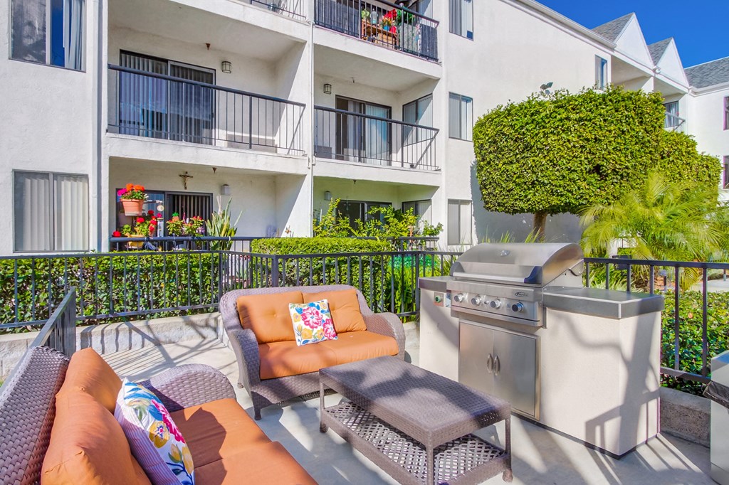 a patio with chairs and a grill and a table