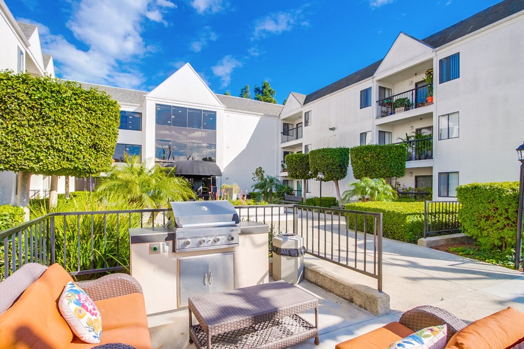 a patio with a grill and a table in front of an apartment building